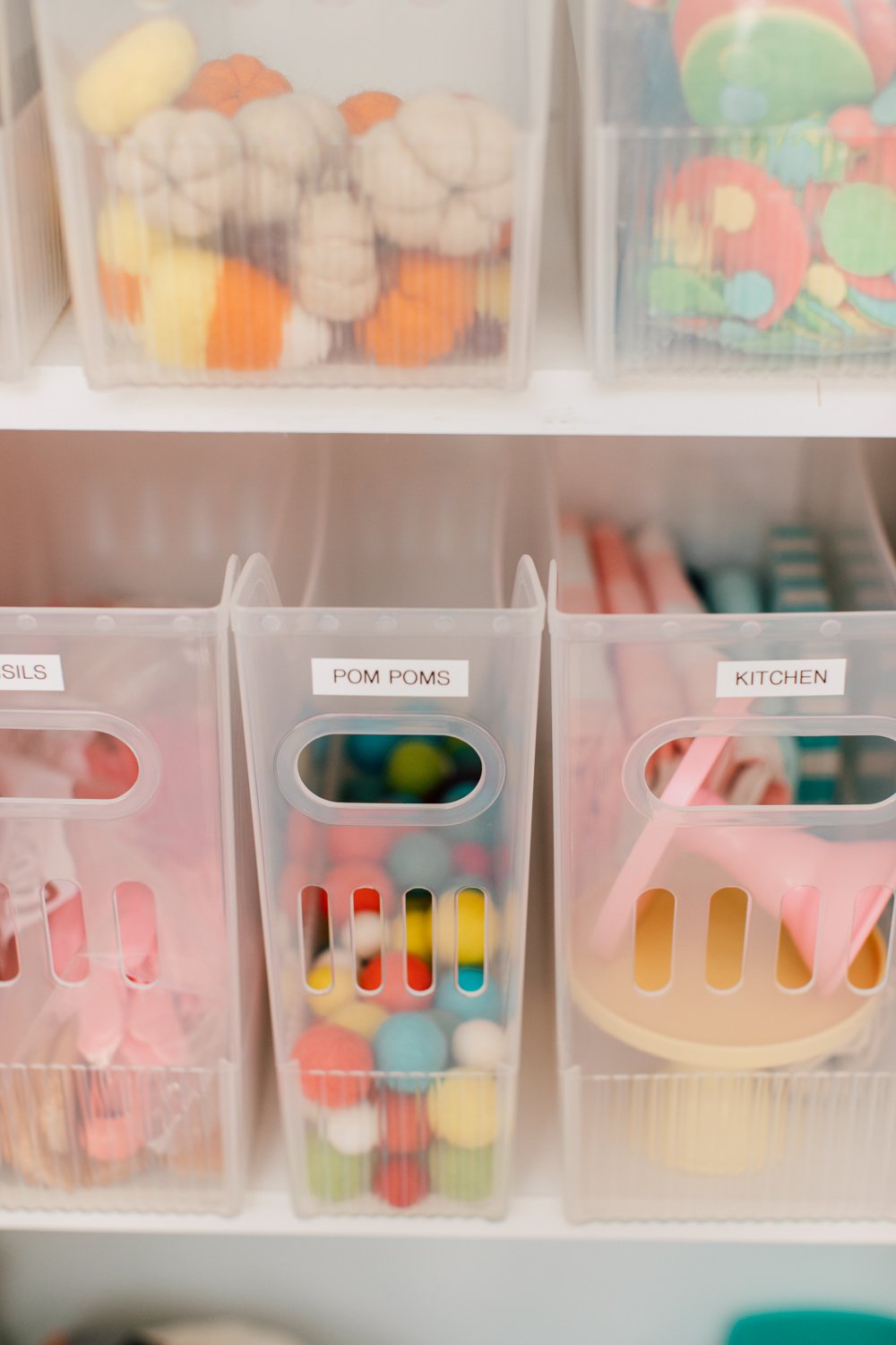 Clear bins with pom poms and kitchen accessories