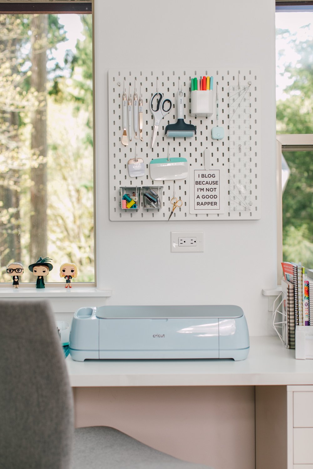 Cricut machine in front of windows with pegboard and Cricut supplies