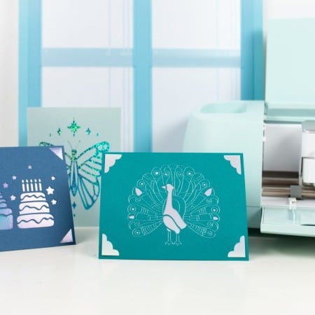 Cricut Explore 3 with Card Mat and three crafted cards.