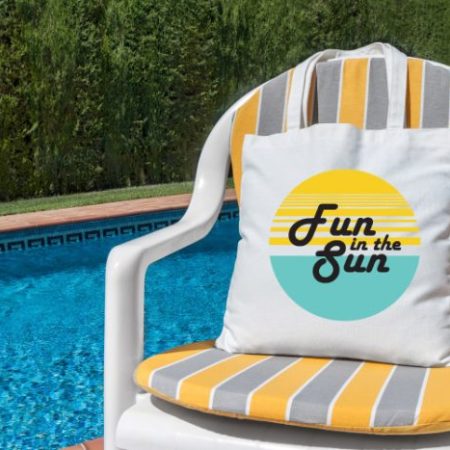 Pillow with the words Fun in the Sun, sitting on a pool side chair