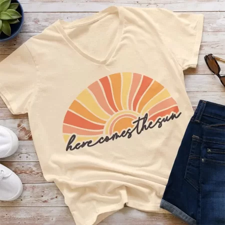 Light yellow t-shirt with a retro sun and the word Here Come the Sun