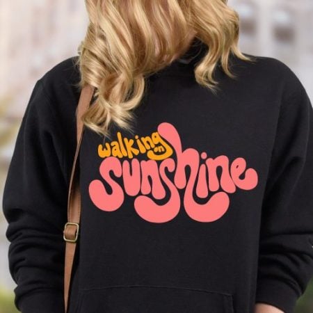 Girl wearing a black sweatshirt with the sayin Walking on Sunshine on the back of it