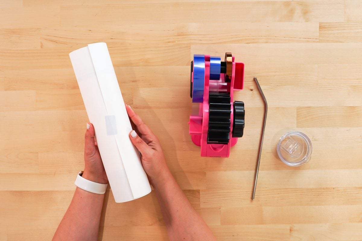 Hands taping butcher paper on a tumbler.