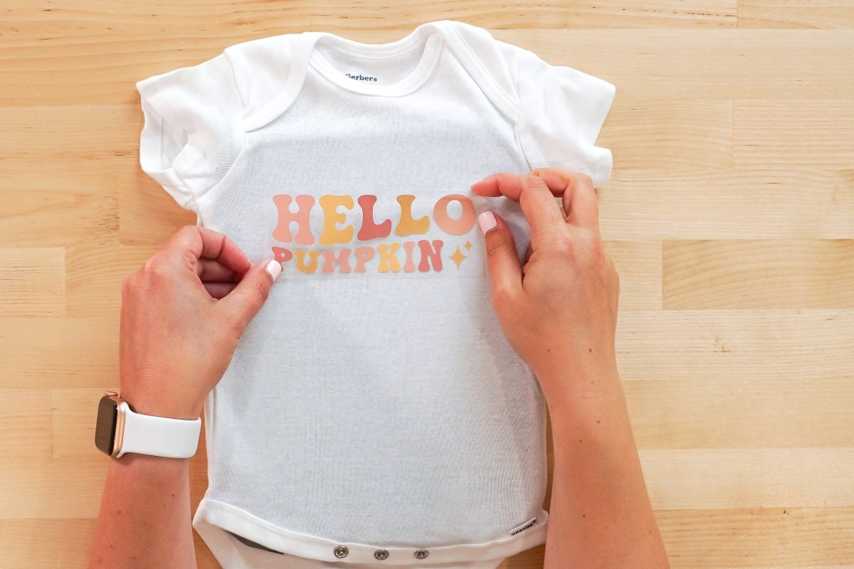 Hands applying the Hello Pumpkin image to the onesie