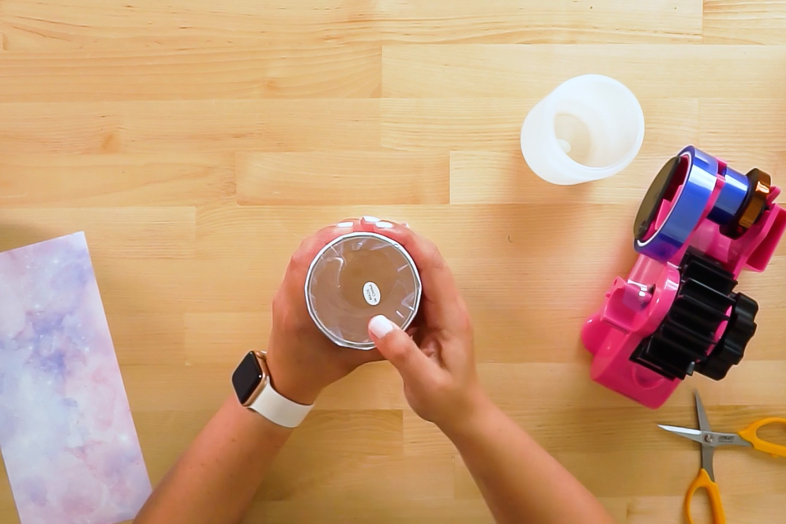 Hands pressing tape on top of tumbler.