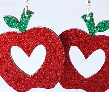 A pair of read apple earrings with a heart shape in the middle of the apple