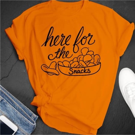 Bright orange t-shirt with an image of a bowl of snacks on it and the saying Here for the Snacks