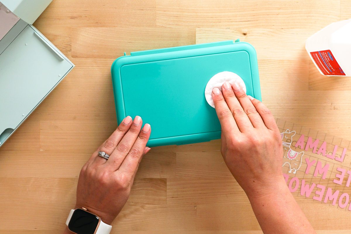 Hands cleaning the pencil box with alcohol.