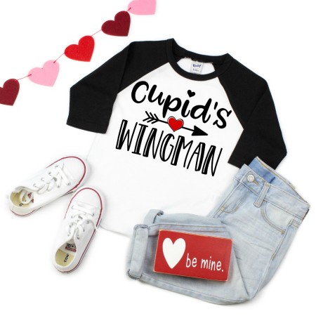 Black and white baseball style shirt that has a heart with an arrow through it and says Cupid's Wingman