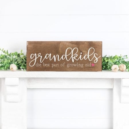 A sign sitting on a fireplace mantel that says, Grandkids the Best Part of Growing Old