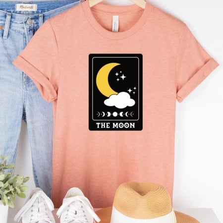 Peach colored t-shirt with an image of a moon tarot card on it