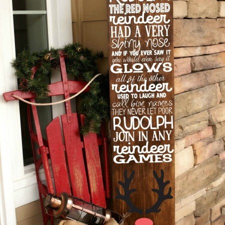 A porch sign decorated with the words to the song, Rudolph the Red-Nosed Reindeer