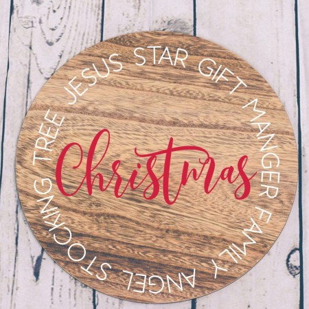A round wooden sign with the word Christmas in the color red