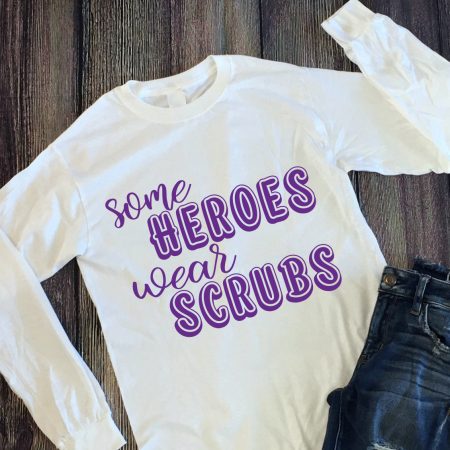 White long sleeved shirt with the words Some Heroes Wear Scrubs