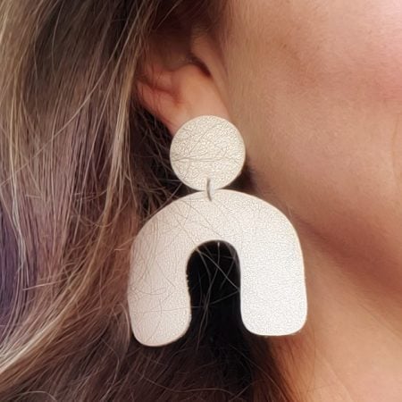 Woman wearing a pair of arch shaped leather earrings