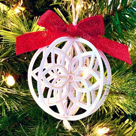 A white homemade Christmas ornament with a red bow on it
