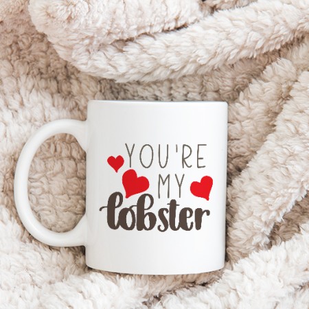White coffee mug decorated with read hearts and the saying You're my Lobster