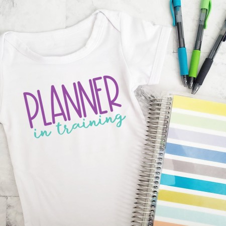 A white onesie with the words Planner in Training on it