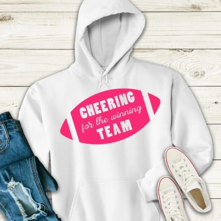 White hooded sweatshirt with an image of a pink football on it and the words Cheering for the Winning Team