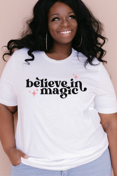 Black plus size model wearing a white shirt that says "believe in magic"