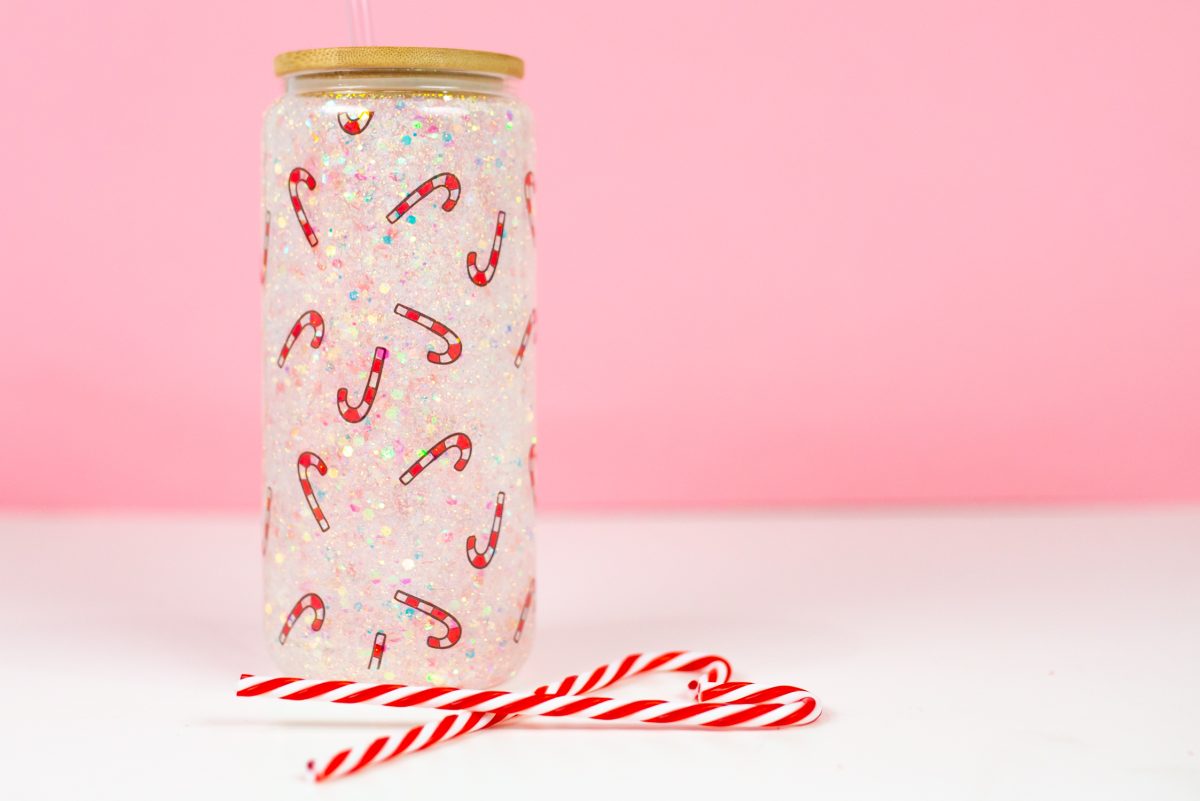 Final candy cane snow globe tumbler with pink background, staged with candy canes