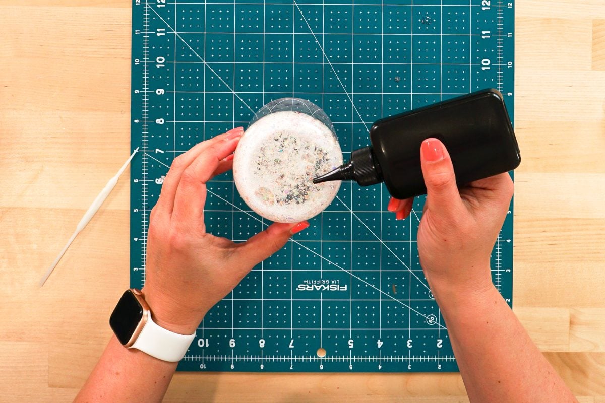 Overhead shot of hands applying the UV resin to the glass can.