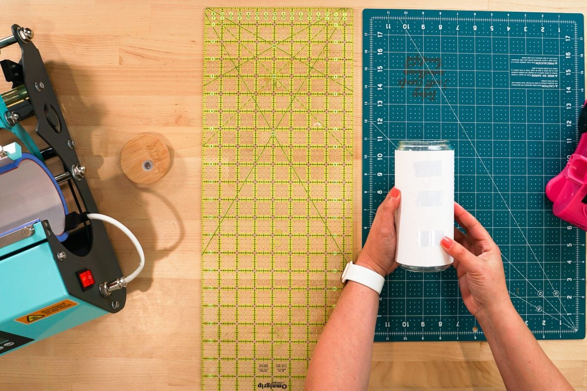 Overhead shot of hands taping transfer to the sublimation tumbler