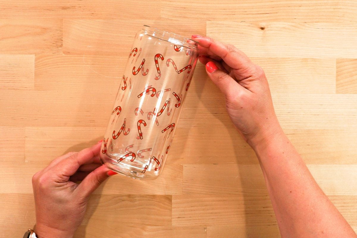 Hands holding candy cane snow globe tumbler after cooling