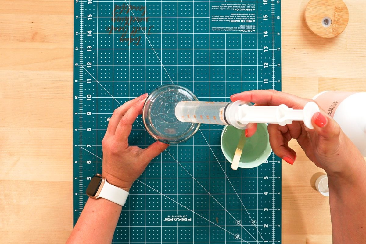 Overhead shot of hands using a syringe to add the glycerine solution to the glass can.