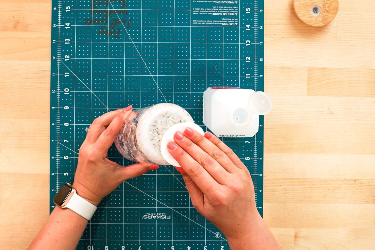 Overhead shot of hands using alcohol wipes to clean the bottom of the can.