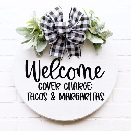 Round door sign with Ribbon and greenery that says Welcome Cover Charge: Tacos and Margaritas