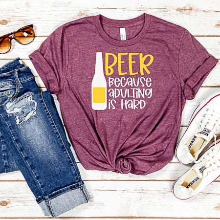 Maroon colored t-shirt with an image of a bottle of beer on it and the saying Beer Because Adulting is Hard