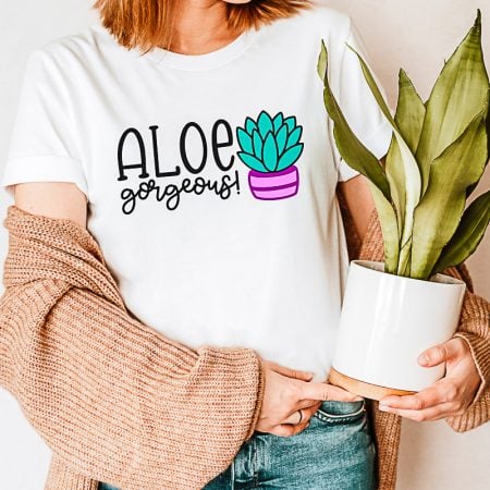Lady wearing a white t-shirt with an image of a plant on it and the saying Aloe Gorgeous on it
