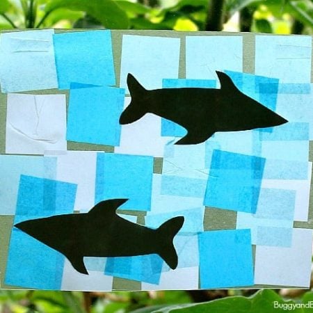 Image of two sharks on a background of multiple hues of blue hanging on a window as a suncatcher