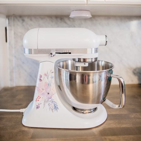 A mixer with a floral decal on it, sitting on a kitchen counter