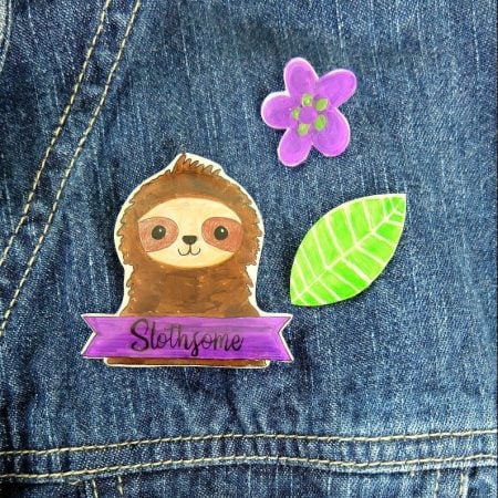 Pins of a sloth, flower and a leaf on a denim jacket