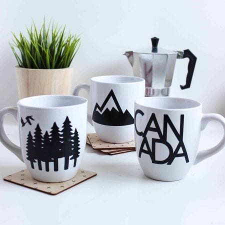 Three white mugs depicting images in honor of Canada Day