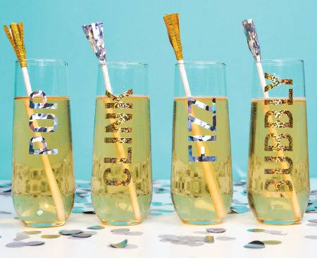 Four champagne glasses decorated with the words pop, clink, fizz and bubbly