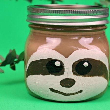 A small Mason jar with a sloth painted on it