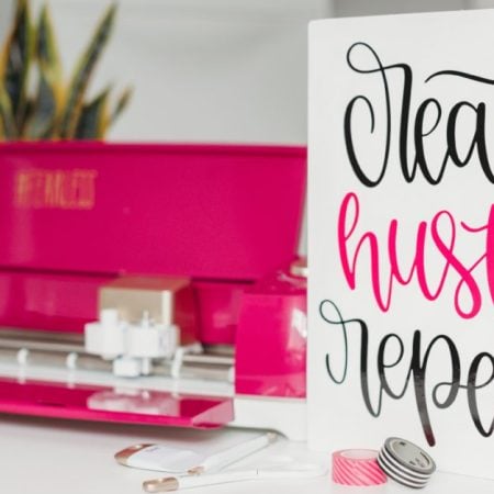 Sign next to a Cricut machine that says Create Hustle Repeat