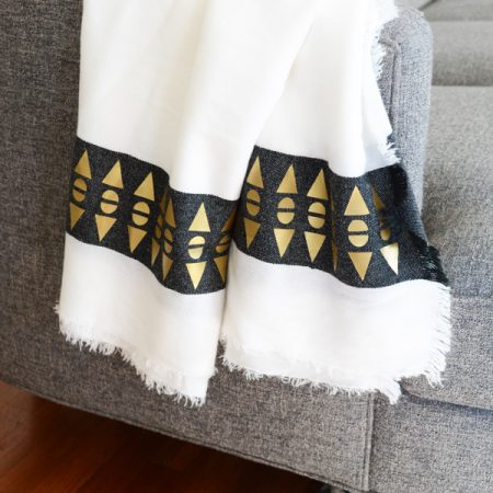 White throw blanket with a design of artsy gold geometric designs on it