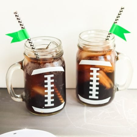 Two mason jars decorated to look like footballs to hold drinks