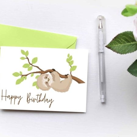 A birthday card with a sloth hanging from a tree branch