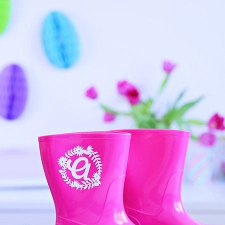 A pair of pink rainboots that have a monogram on them
