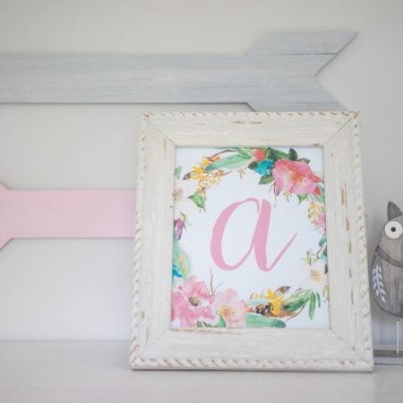 A white frame with a picture of the initial "a" and flowers around it