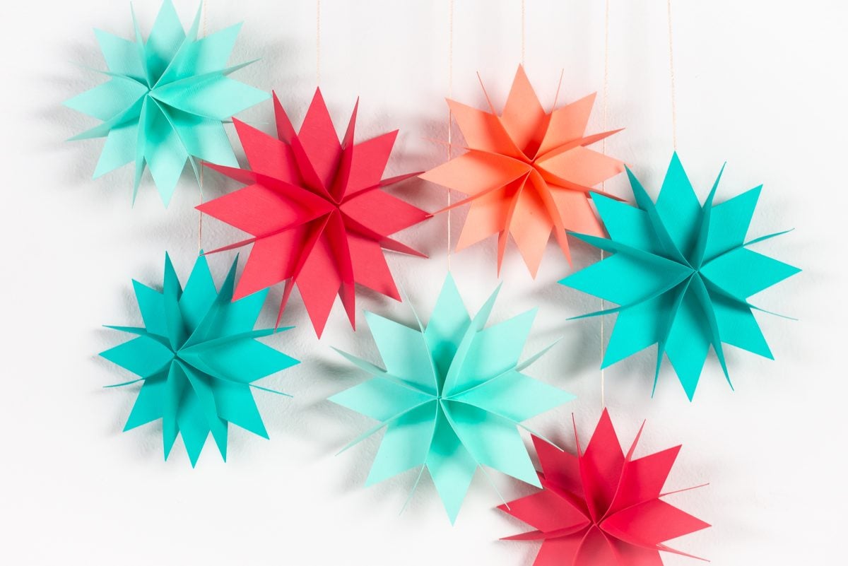 Brightly colored paper Christmas stars hanging over white wall