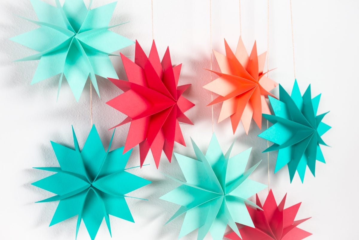 Brightly colored paper Christmas stars hanging over white wall