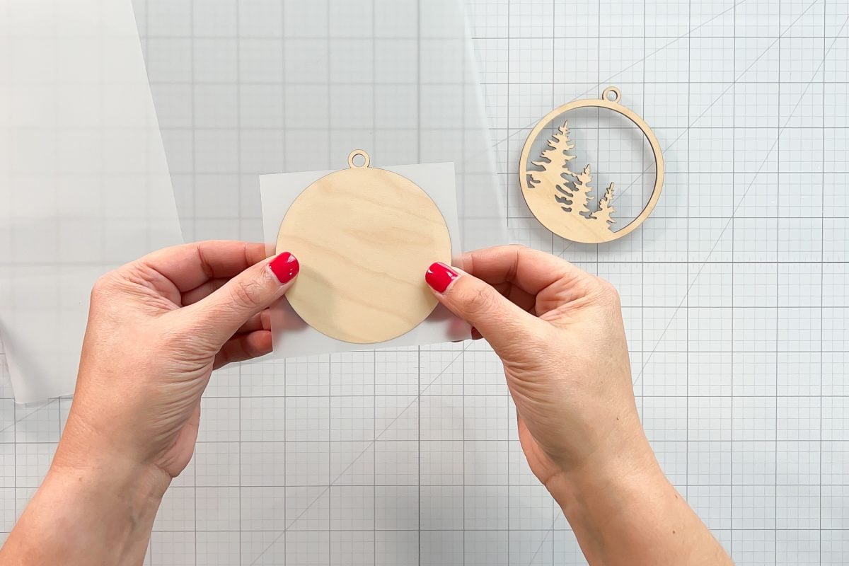 Hands showing piece of laminate cut the size of the ornament.