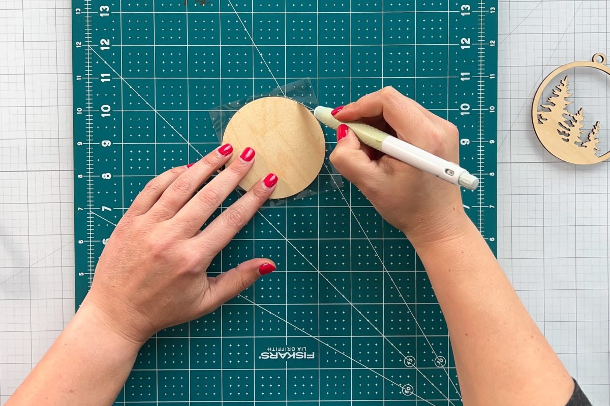 Hands using craft knife to cut off excess laminate sheet