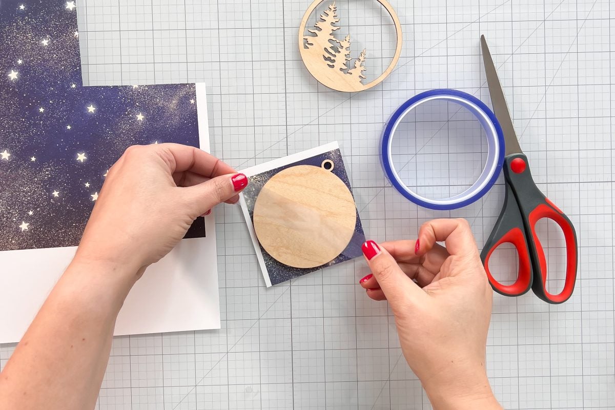 Hands pulling pull off the paper to reveal the sublimated image on wood